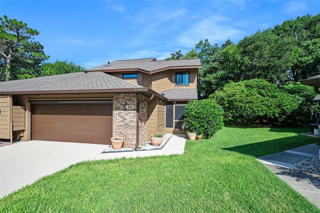 A two-story brown house with a garage, brick accents, and a landscaped front yard — 99 OLD BARN TRAIL, ORMOND BEACH, FL