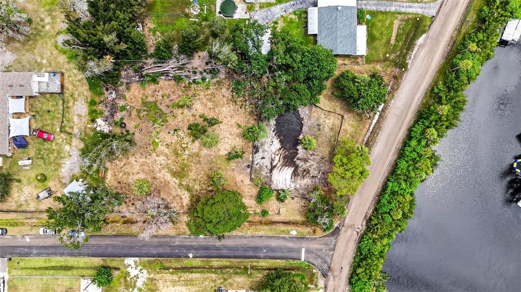 This aerial view shows a vacant, partially cleared residential lot situated next to a waterway — 409 1ST AVENUE NW, RUSKIN, FL