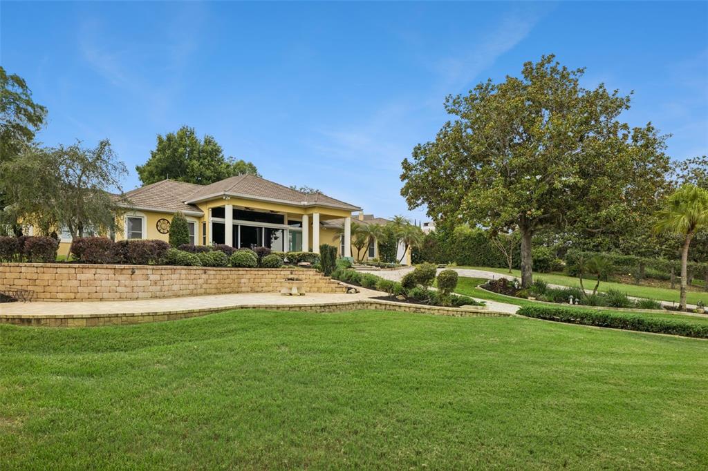 A yellow house with a stone driveway, a screened-in patio, and a detached garage — 12128 LAKESHORE DRIVE, CLERMONT, FL