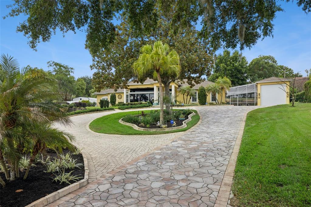 A large yellow house with a stone retaining wall overlooks a spacious green lawn — 12128 LAKESHORE DRIVE, CLERMONT, FL