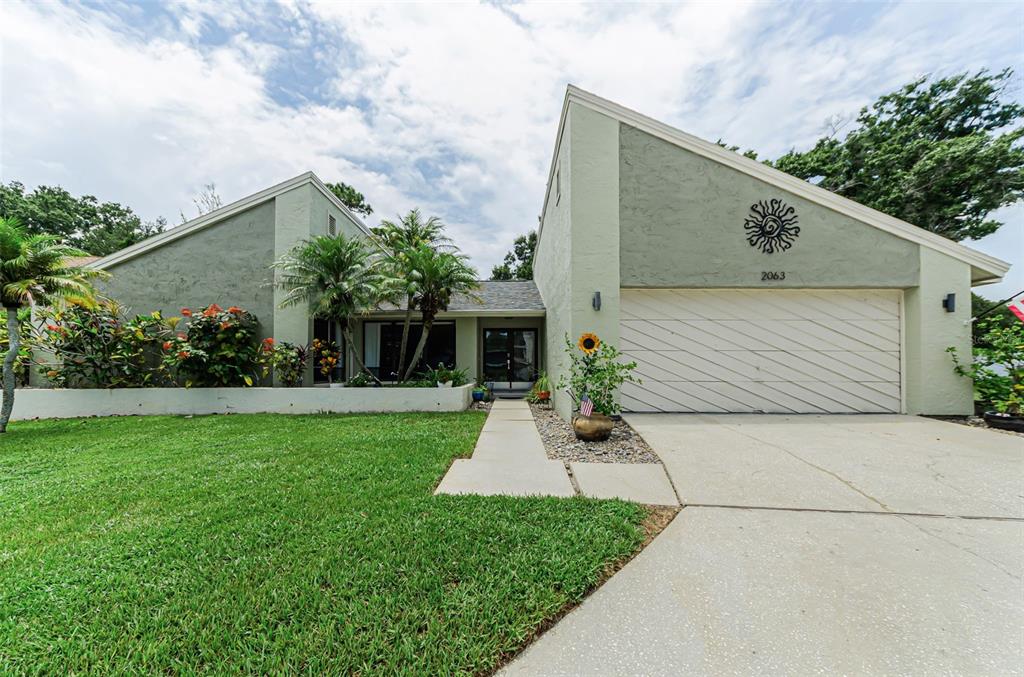 A single-story house with a light green exterior, a two-car garage, and a front lawn — 2063 BROOKSIDE DRIVE, SAFETY HARBOR, FL