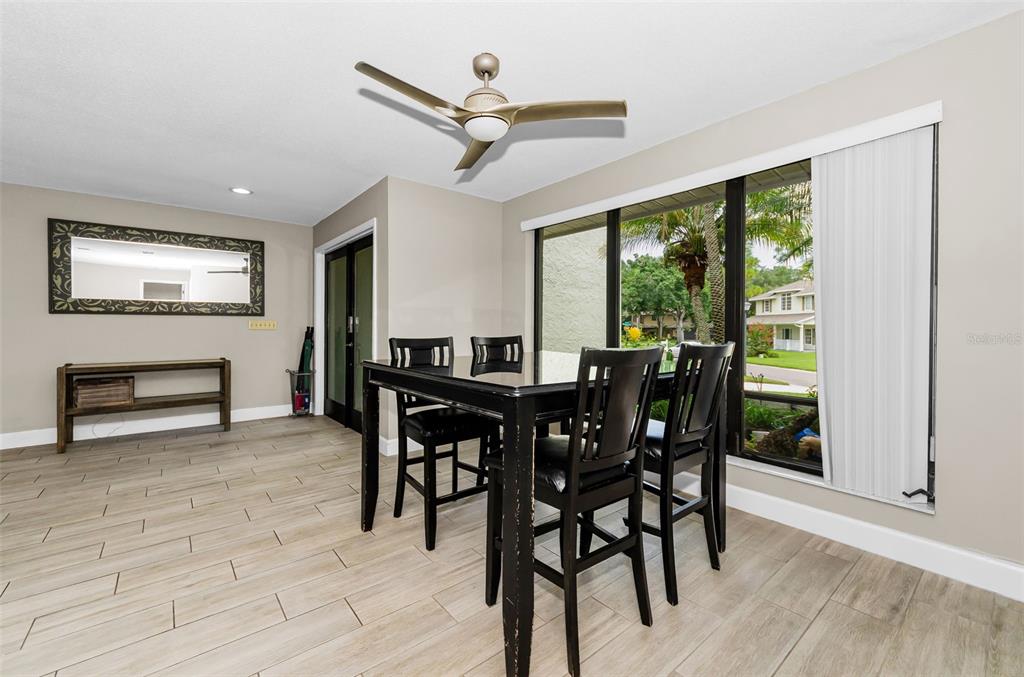 A dining room features a dark wood table, matching chairs, tile flooring, and a large window — 2063 BROOKSIDE DRIVE, SAFETY HARBOR, FL