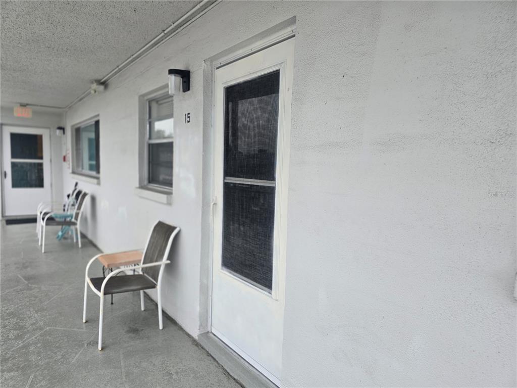 A white exterior wall features a door labeled 15, a window, and outdoor chairs — 5356 81ST STREET N UNIT 15, ST PETERSBURG, FL