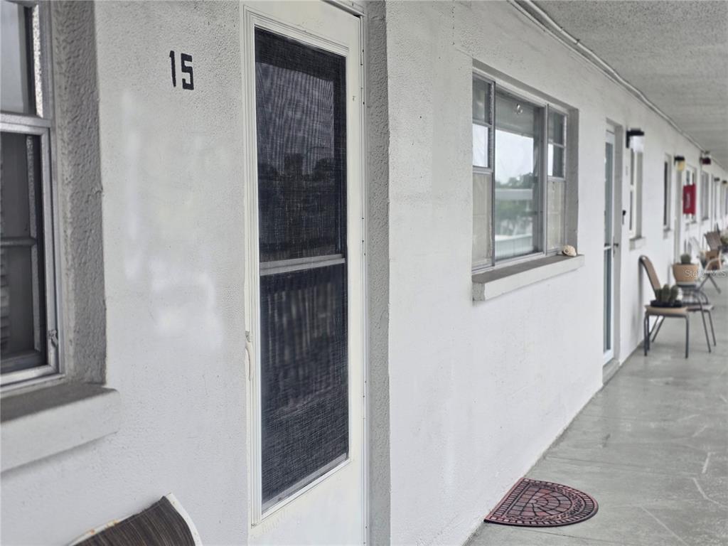 A view of an exterior apartment walkway featuring unit number 15, windows, and a door — 5356 81ST STREET N UNIT 15, ST PETERSBURG, FL