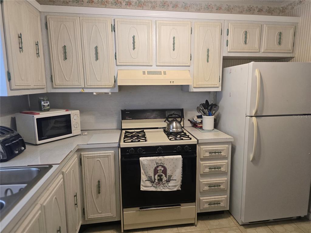 A kitchen features light-colored wood cabinets, white appliances, and a gas range — 5356 81ST STREET N UNIT 15, ST PETERSBURG, FL
