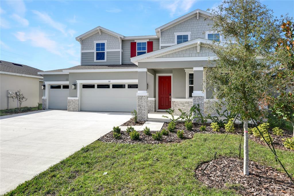 A two-story suburban house features a gray exterior, a red front door, and a three-car garage — 161 WATERSTONE LOOP, TAVARES, FL