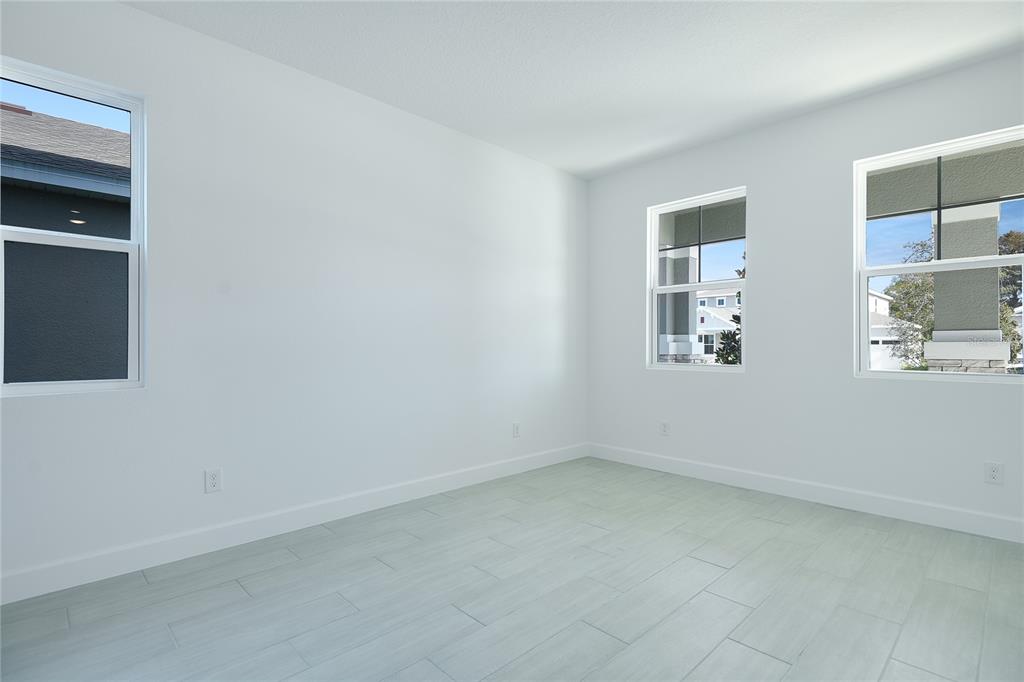 An empty room with white walls, light-colored tile flooring, and three windows — 161 WATERSTONE LOOP, TAVARES, FL