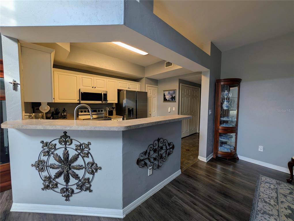 A kitchen with white cabinets, stainless steel appliances, and a breakfast bar with decorative metalwork — 2717 NW 103RD WAY UNIT O, GAINESVILLE, FL