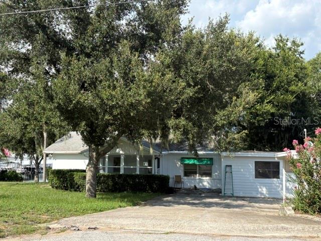 A single-story white house with a concrete driveway and large trees in the front yard — 964 OHLINGER ROAD, BABSON PARK, FL