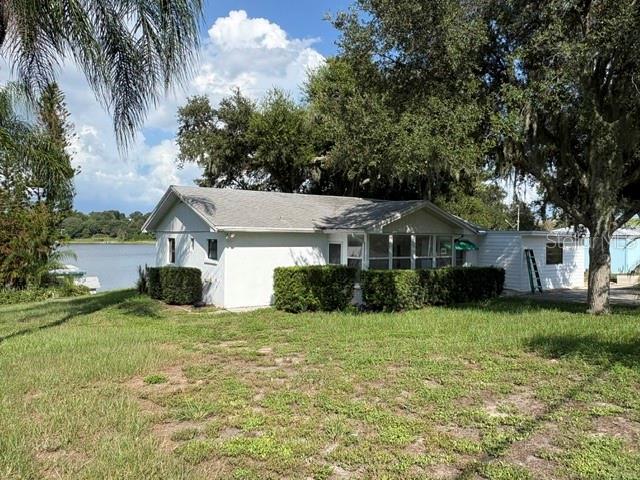 A white single-story house with a screened porch sits on a grassy lot near water — 964 OHLINGER ROAD, BABSON PARK, FL