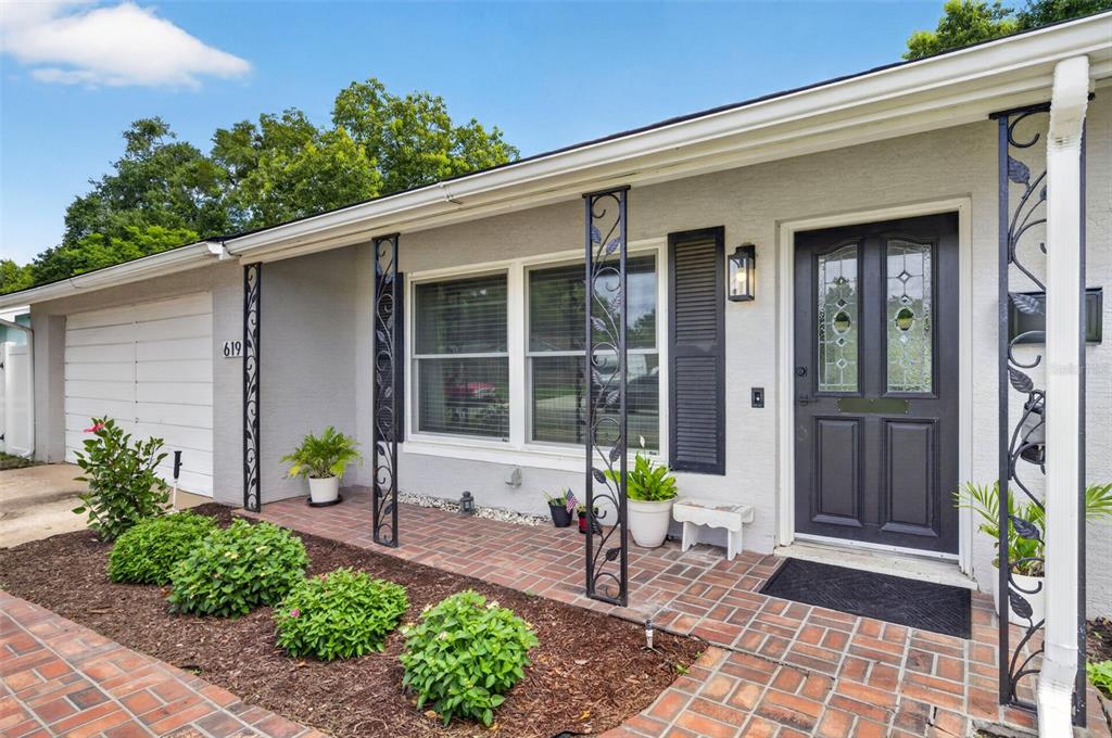 The exterior of a gray house features a brick porch, decorative iron columns, and landscaping — 619 MARSHALL STREET, ALTAMONTE SPRINGS, FL