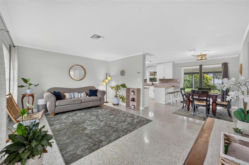 A living room with a grey sofa, area rug, and an open-concept kitchen and dining area — 619 MARSHALL STREET, ALTAMONTE SPRINGS, FL