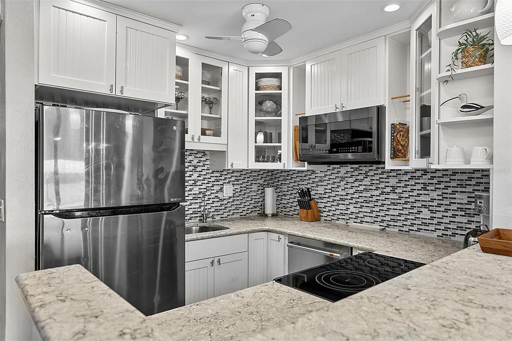 A kitchen features white cabinetry, stainless steel appliances, granite countertops, and a black-and-white tiled backsplash — 51 S OCEAN PALM DRIVE, FLAGLER BEACH, FL