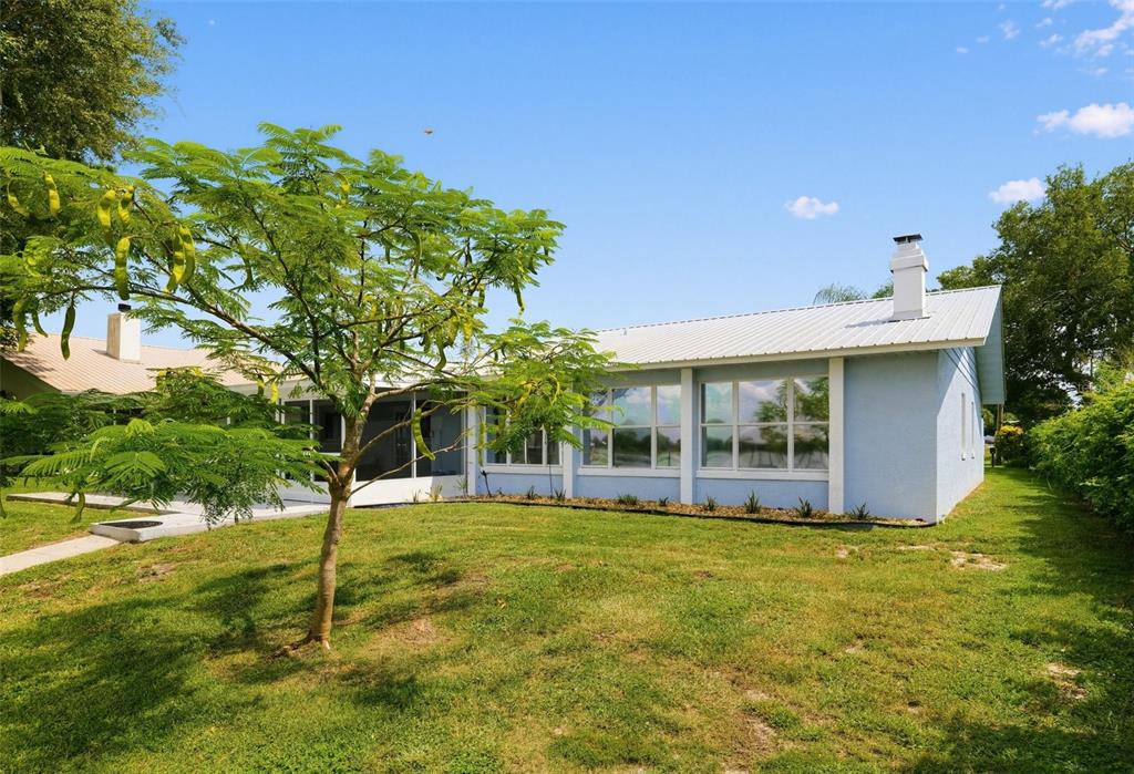 A light blue house with a large screened-in porch and a concrete patio in the backyard — 186 MANDOLIN DRIVE, LAKE PLACID, FL