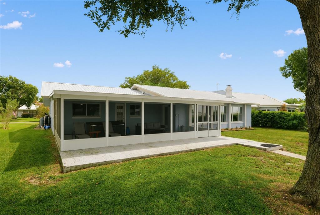 A single-story blue house with a metal roof and a pontoon boat in the driveway — 186 MANDOLIN DRIVE, LAKE PLACID, FL
