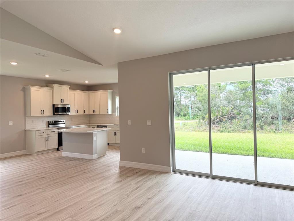A living room features light wood-look flooring, a grey sofa, and a black console table — 5336 COLUMBUS BOULEVARD, SEBRING, FL