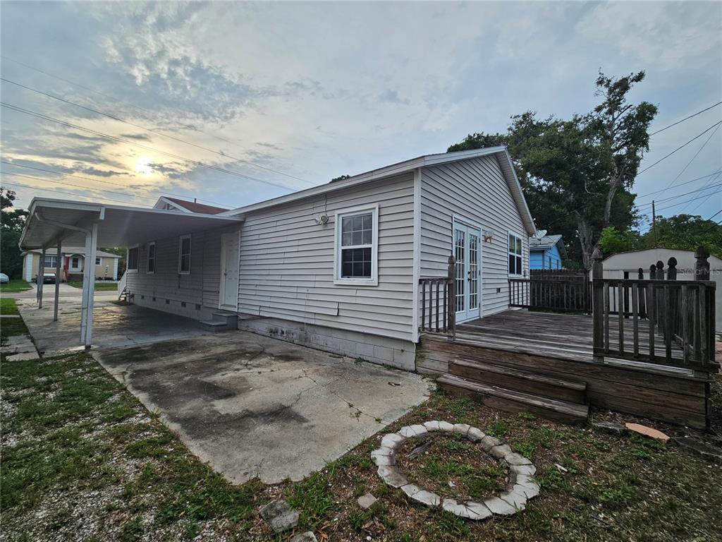 A side view of a house featuring a carport, a wooden deck, and a concrete patio — 2434 37TH STREET S, ST PETERSBURG, FL