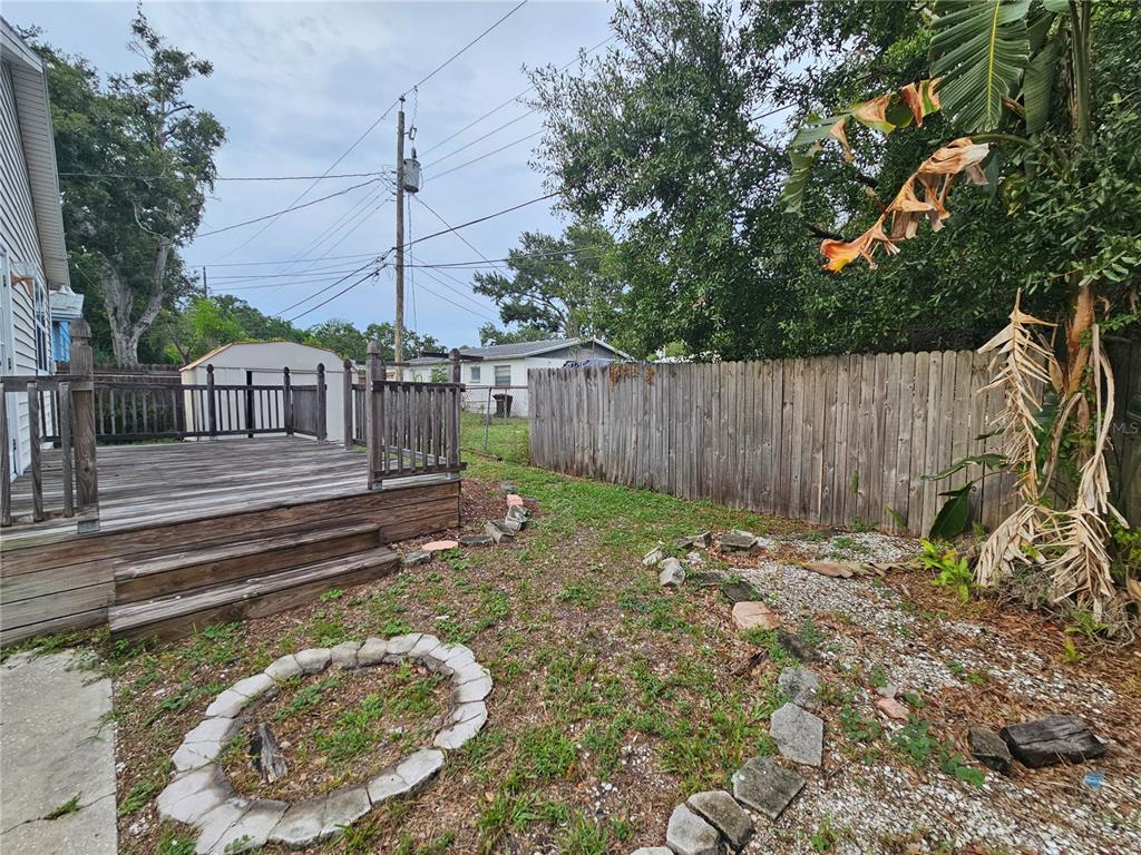 A backyard features a wooden deck, a stone fire pit, and a wooden privacy fence — 2434 37TH STREET S, ST PETERSBURG, FL