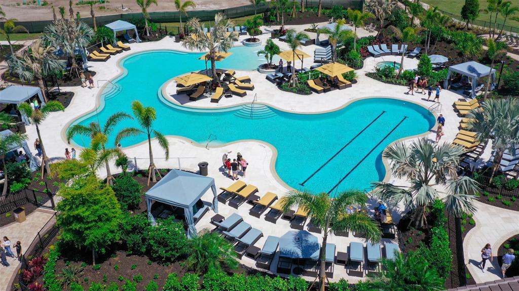 An aerial view of a resort-style swimming pool surrounded by lounge chairs, cabanas, and landscaping — 3723 COUNTRY VIEW COURT, BRADENTON, FL