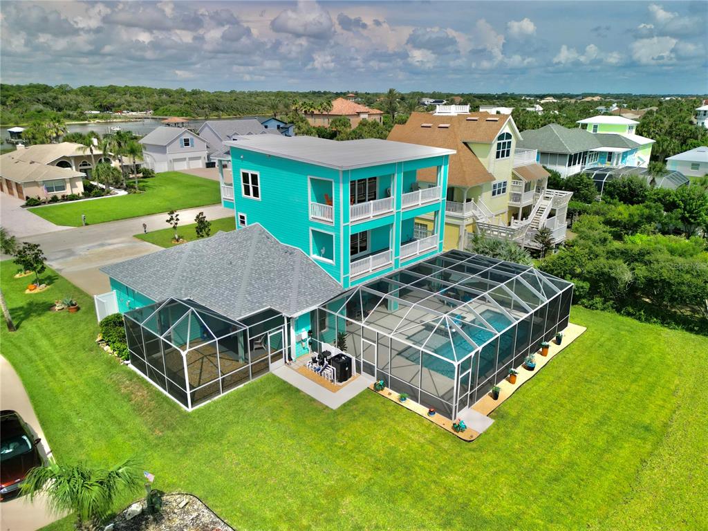 An aerial view of a bright turquoise three-story house with a screened pool and patio — 3073 PAINTERS WALK, FLAGLER BEACH, FL