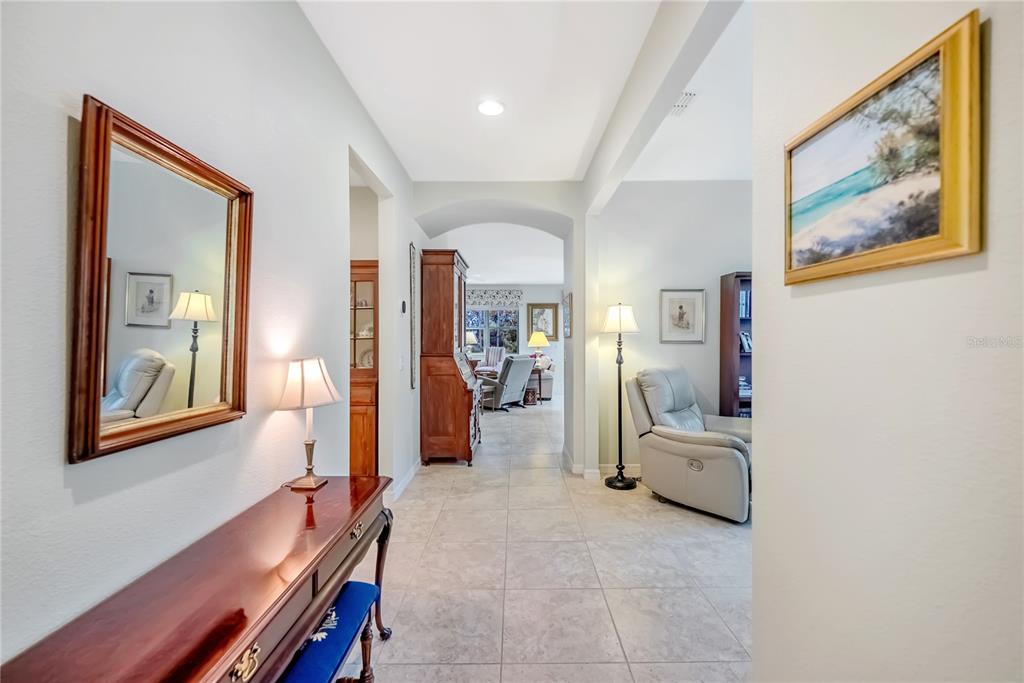 A tiled hallway leads past a console table and mirror toward an open living area — 9145 SW 70TH LOOP, OCALA, FL