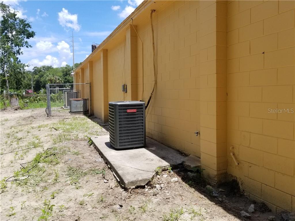 A Goodman air conditioning unit sits on a concrete pad beside a yellow block wall — 3520 W HIGHWAY 326 HIGHWAY, OCALA, FL