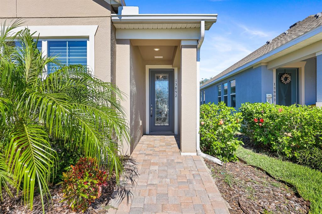 A paved walkway leads to the front entrance of a house with a glass-paneled door — 13892 KINGFISHER GLEN DRIVE, LITHIA, FL