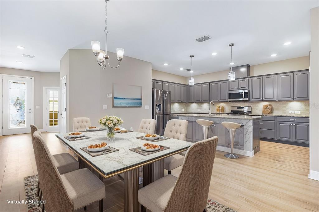 A dining area with a marble-topped table opens into a kitchen with gray cabinets — 13892 KINGFISHER GLEN DRIVE, LITHIA, FL