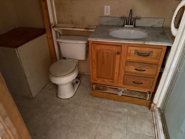 A bathroom features a white toilet, a wooden vanity with a sink, and tiled flooring — 1600 E LAKEVIEW AVENUE, EUSTIS, FL