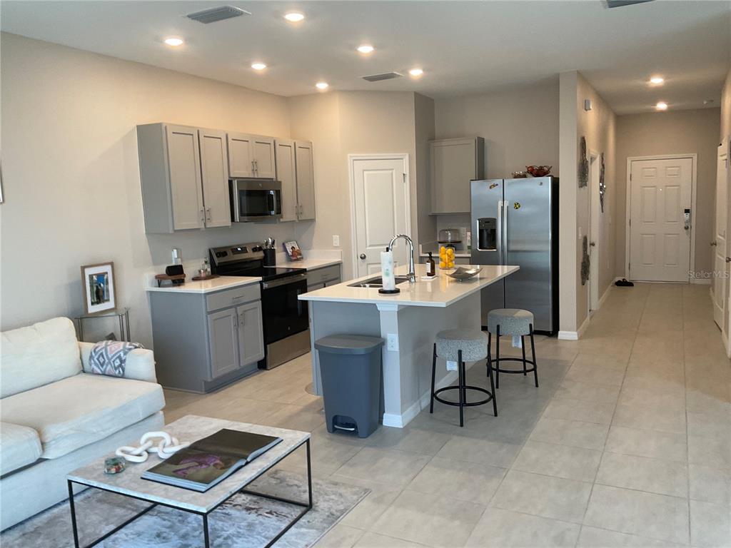 An open-concept kitchen features gray cabinetry, stainless steel appliances, and a central island with seating — 7633 WATERSCAPE DRIVE, GROVELAND, FL