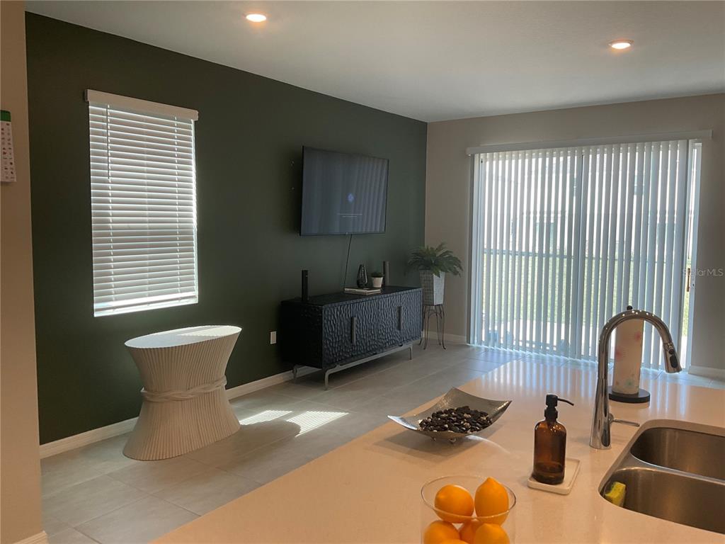 A kitchen island overlooks a living area with a dark green accent wall and television — 7633 WATERSCAPE DRIVE, GROVELAND, FL