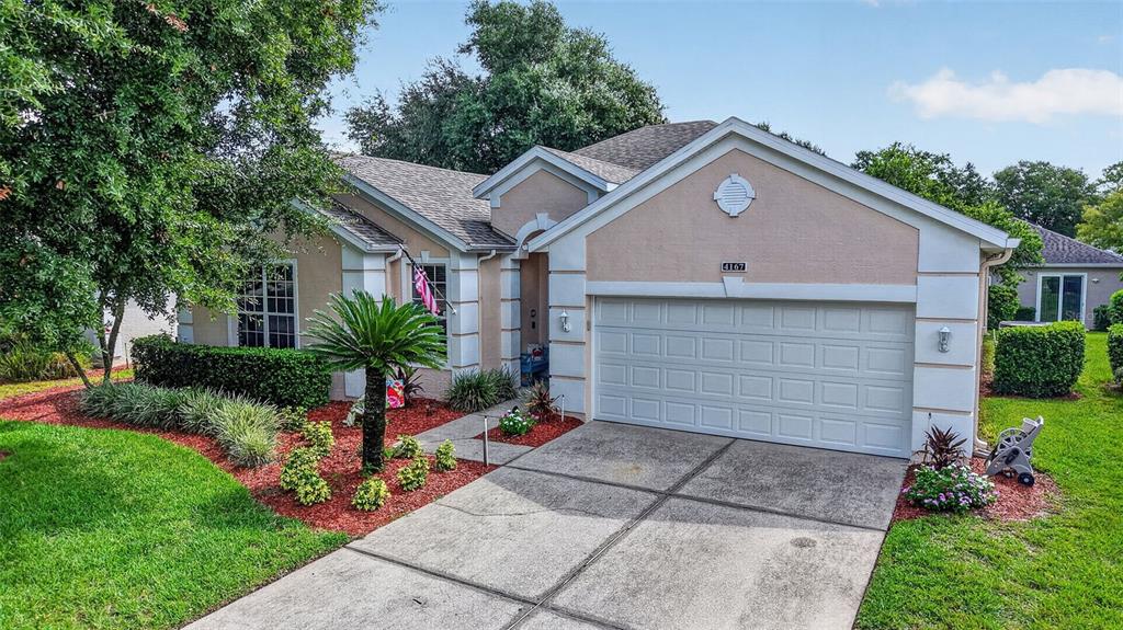A single-story house with a beige stucco exterior, a two-car garage, and a landscaped front yard — 4167 NEWLAND STREET, CLERMONT, FL