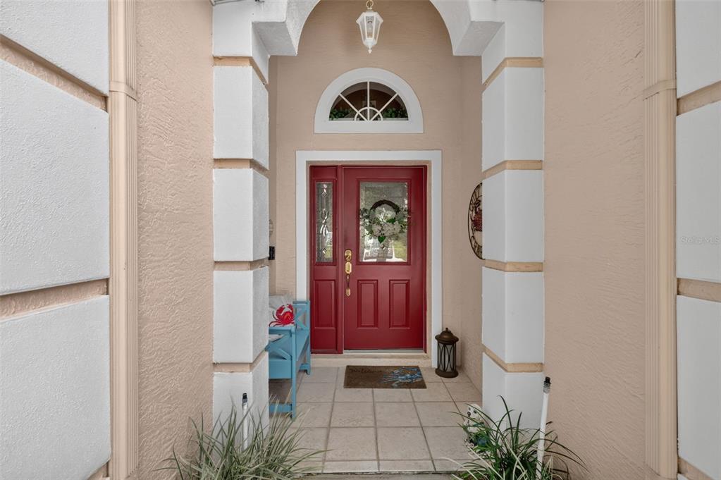 A red front door is framed by white columns under an arched entryway — 4167 NEWLAND STREET, CLERMONT, FL