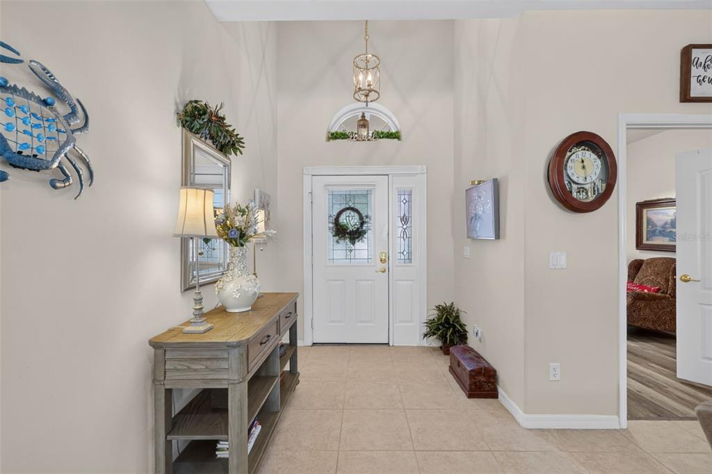 An entryway features a console table, a front door with a transom window, and tile flooring — 4167 NEWLAND STREET, CLERMONT, FL