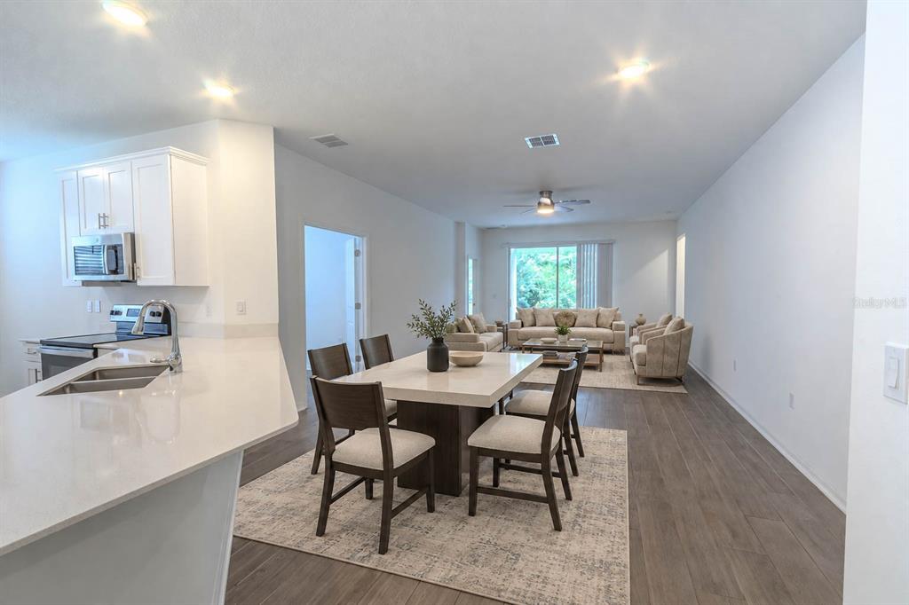 A kitchen with white cabinets and an island opens into a spacious living area — 407 THREE OAKS DRIVE, EDGEWATER, FL