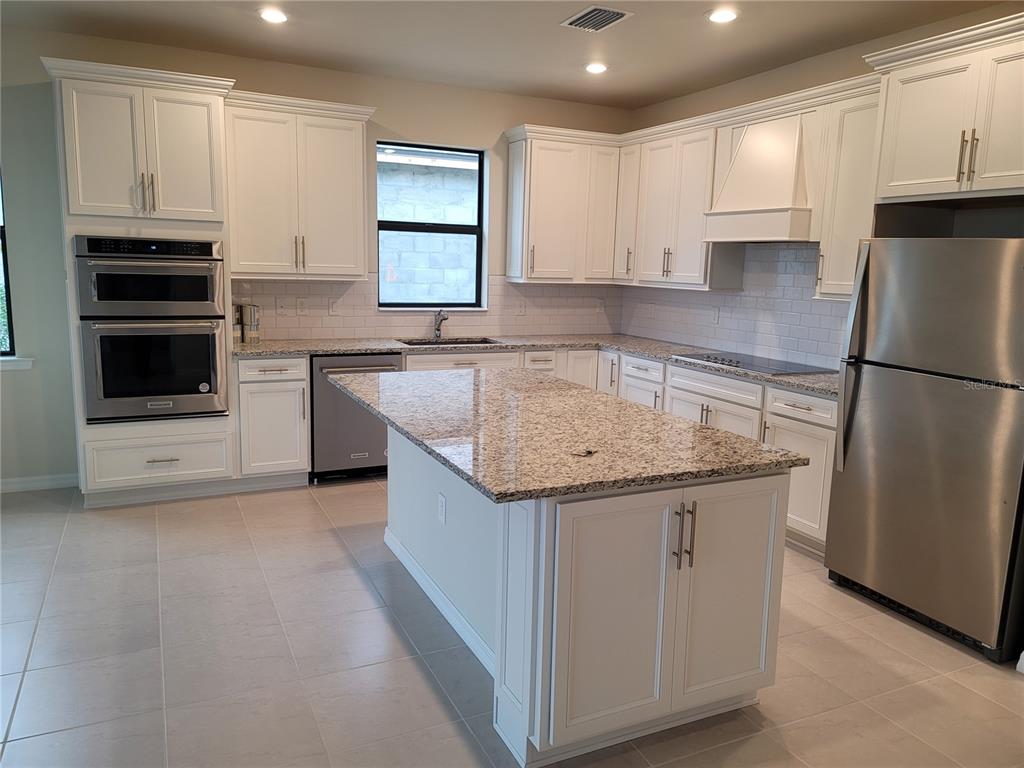 A kitchen features white cabinets, granite countertops, stainless steel appliances, and a central island — 2530 BUCKTHORN LOOP, NORTH PORT, FL