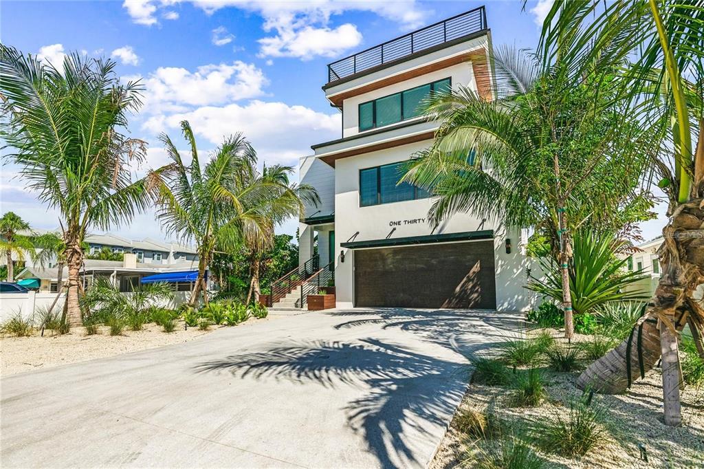 A modern three-story house with a concrete driveway, palm trees, and a rooftop deck — 135 GRANT DRIVE, SARASOTA, FL