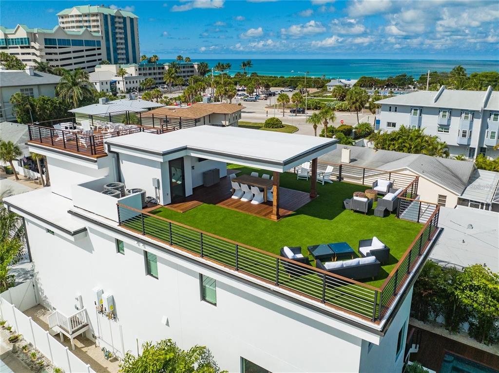 An elevated view of a modern rooftop terrace featuring artificial turf, patio furniture, and decking — 135 GRANT DRIVE, SARASOTA, FL