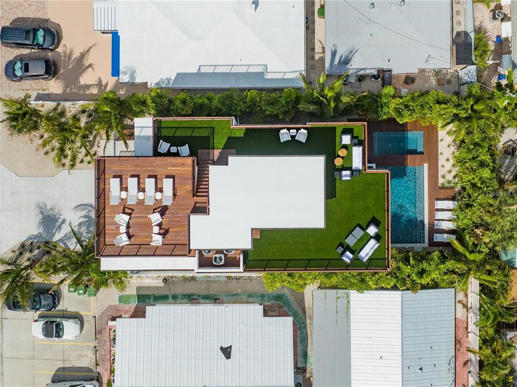 An aerial view shows a modern house with a rooftop deck, artificial turf, and swimming pool — 135 GRANT DRIVE, SARASOTA, FL
