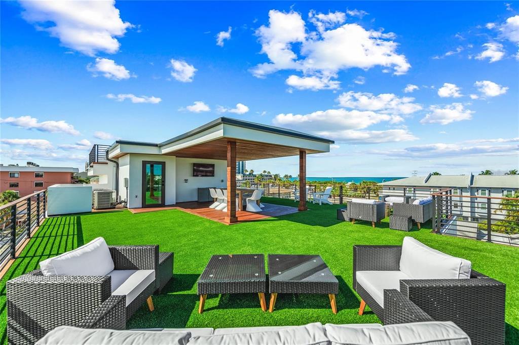 A rooftop terrace features artificial turf, a covered dining area, and outdoor lounge furniture — 135 GRANT DRIVE, SARASOTA, FL