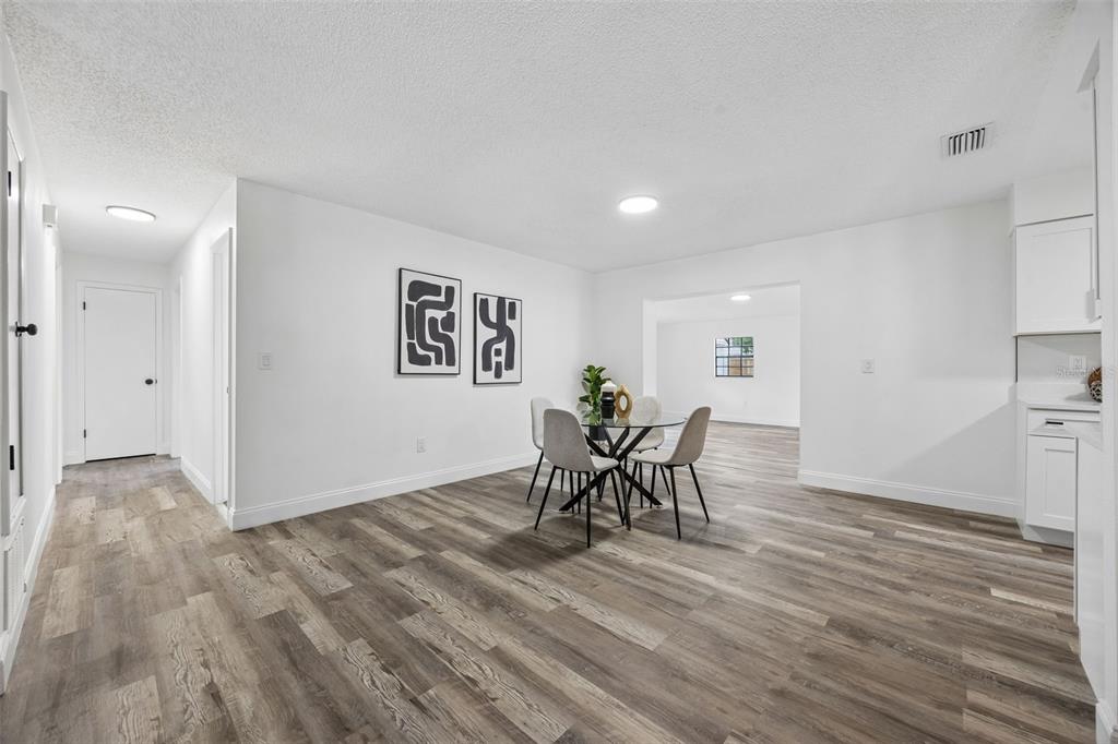 A dining area features light wood-look flooring, white walls, and a glass-topped table with chairs — 1660 ASHWOOD AVENUE, TITUSVILLE, FL