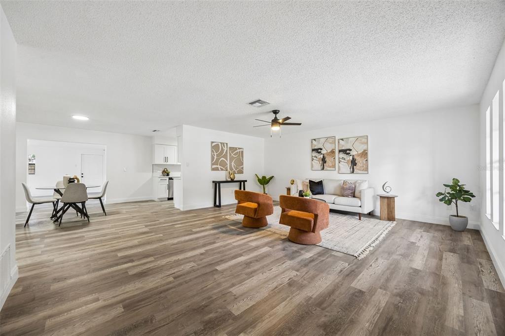 An open-concept living and dining area features light wood-look flooring and a ceiling fan — 1660 ASHWOOD AVENUE, TITUSVILLE, FL