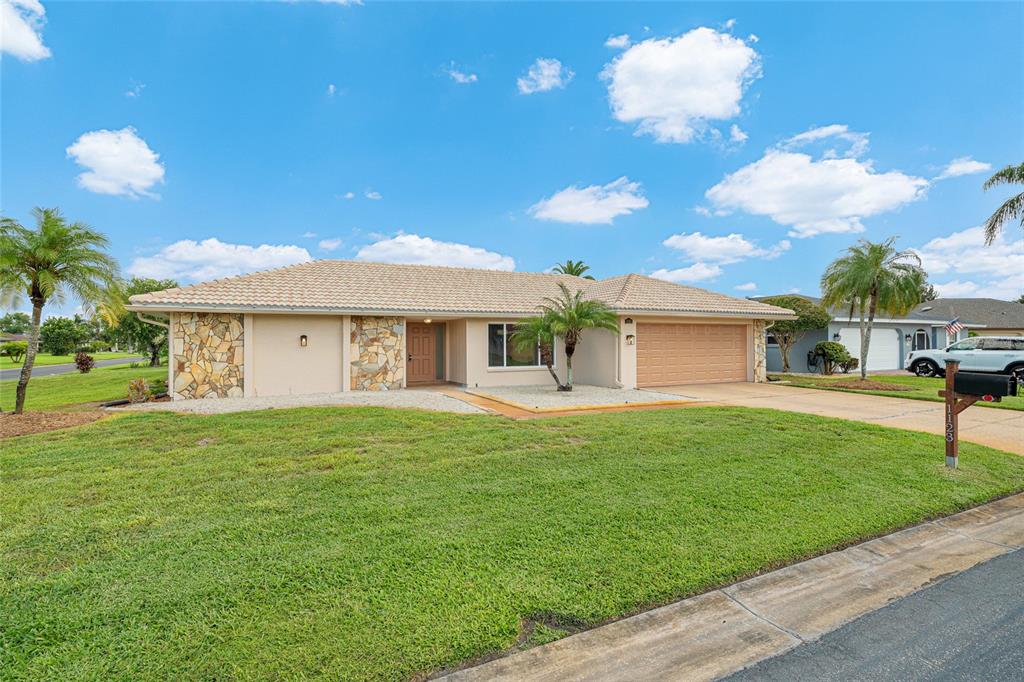 A single-story house with a tan exterior, stone accents, and a two-car garage — 1123 MISTI COURT, VENICE, FL