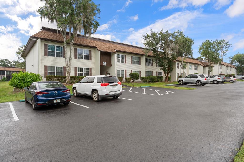 A multi-story apartment building with a parking lot in front featuring several parked cars — 2400 FOREST DRIVE UNIT 252, INVERNESS, FL
