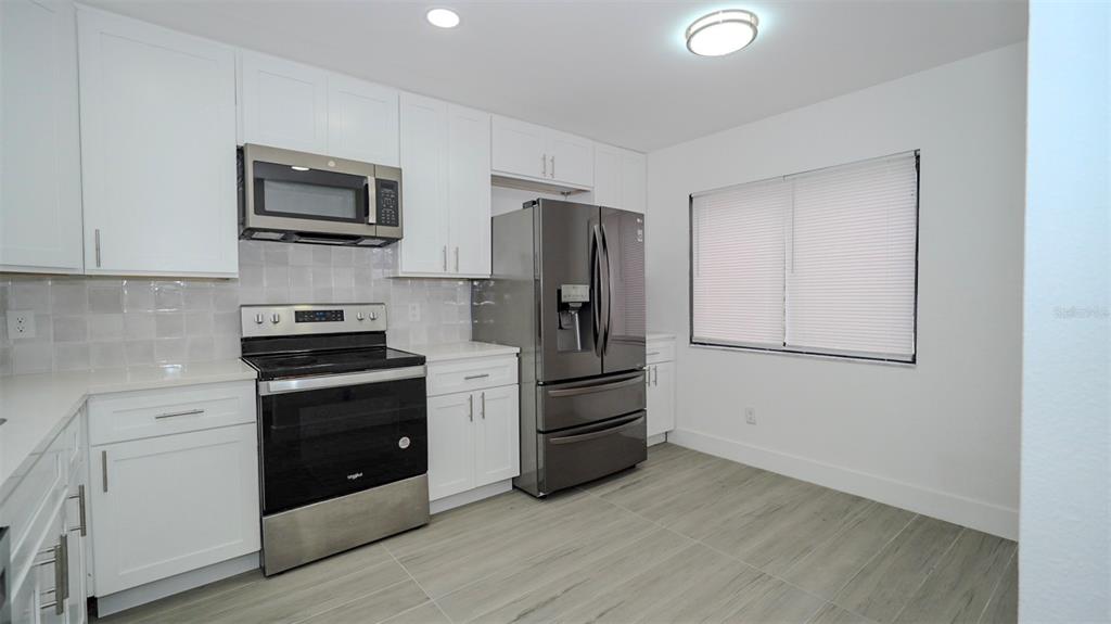 A modern kitchen features white cabinetry, stainless steel appliances, and light-colored tile flooring — 4368 S LAKE ORLANDO PARKWAY UNIT 203, ORLANDO, FL
