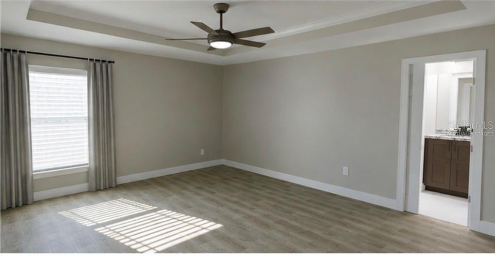 An empty bedroom with light wood-look flooring, a ceiling fan, and an attached bathroom — 50 BAY DRIVE, OCKLAWAHA, FL