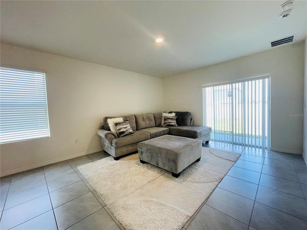 A living room features a grey sectional sofa, a matching ottoman, and tile flooring — 17043 OVAL RUM DRIVE, WIMAUMA, FL