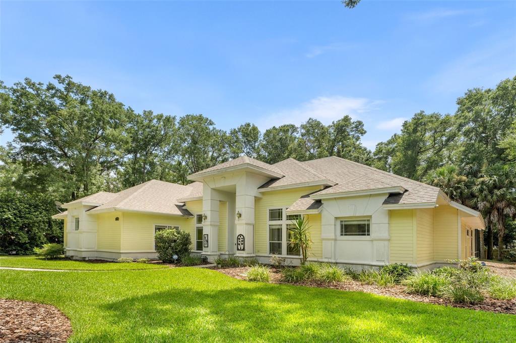 A yellow, single-story house with a prominent white entryway stands on a grassy lawn — 9627 SW 40TH LANE, GAINESVILLE, FL