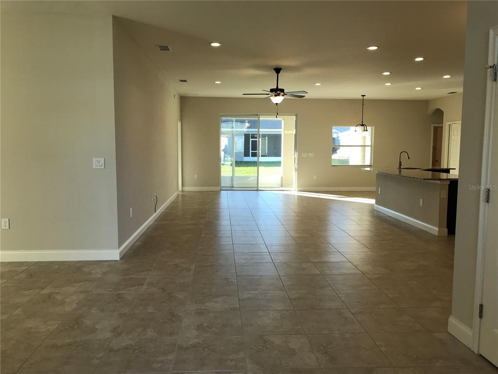 An open-concept living and dining area features tile flooring, recessed lighting, and a sliding glass door — 6063 HIGHLANDS GRACE BOULEVARD, LAKELAND, FL