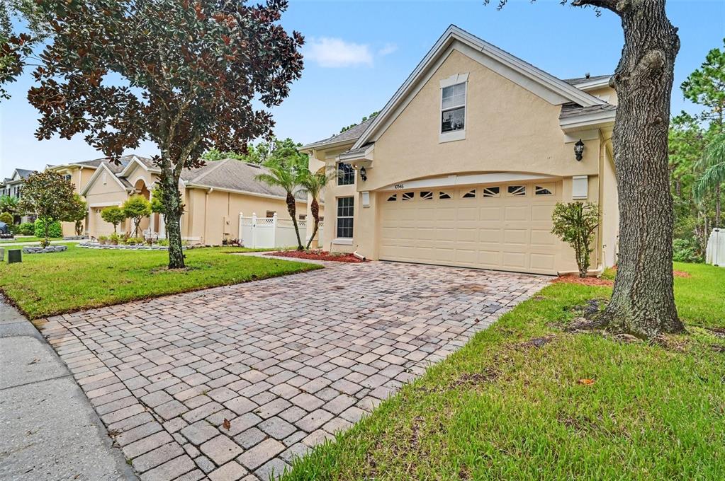 A beige house with a paved driveway, a two-car garage, and a front lawn — 10546 WILLOW RIDGE LOOP, ORLANDO, FL